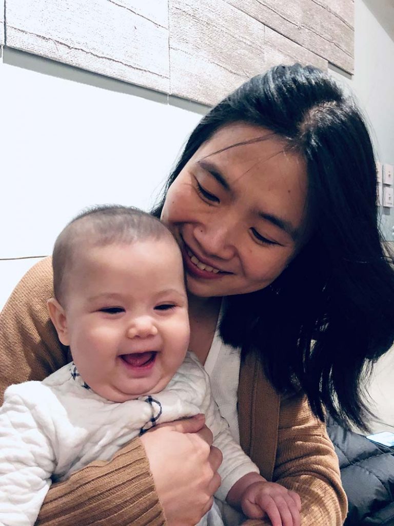 Dr. Hui Shen smiling while holding smiling baby 