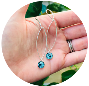 Small teal earrings being held in palm of hand