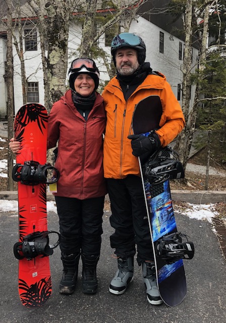 Penny Free and her husband, dressed in winter gear, holding snowboards