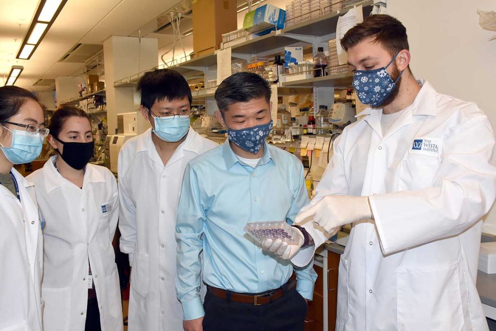 Dr. Zhang examining specimen with team in research lab