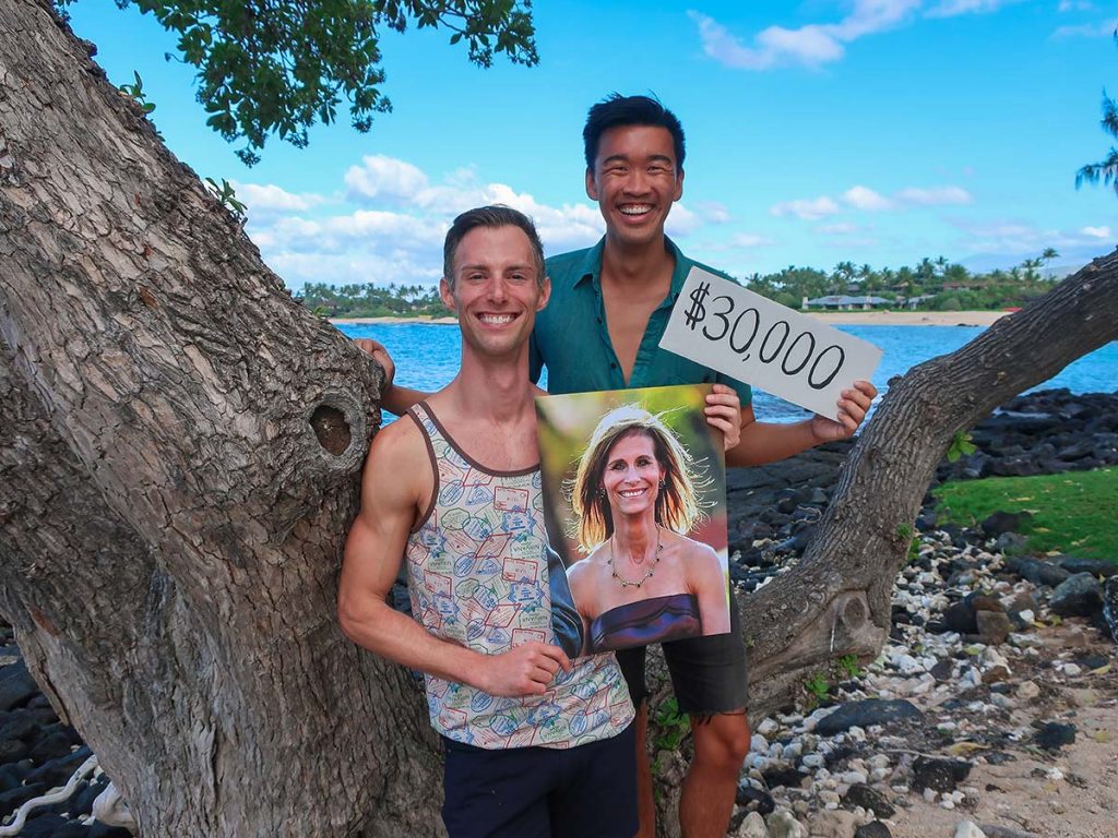 Jonathan with partner outdoors, holding sign with portrait of his mother, and partner holding sign that says, $30,000
