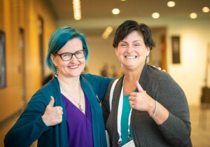 woman with teal hair and friend giving thumbs up sign