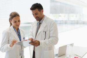 two doctors in lab coats looking at paperwork and discussing