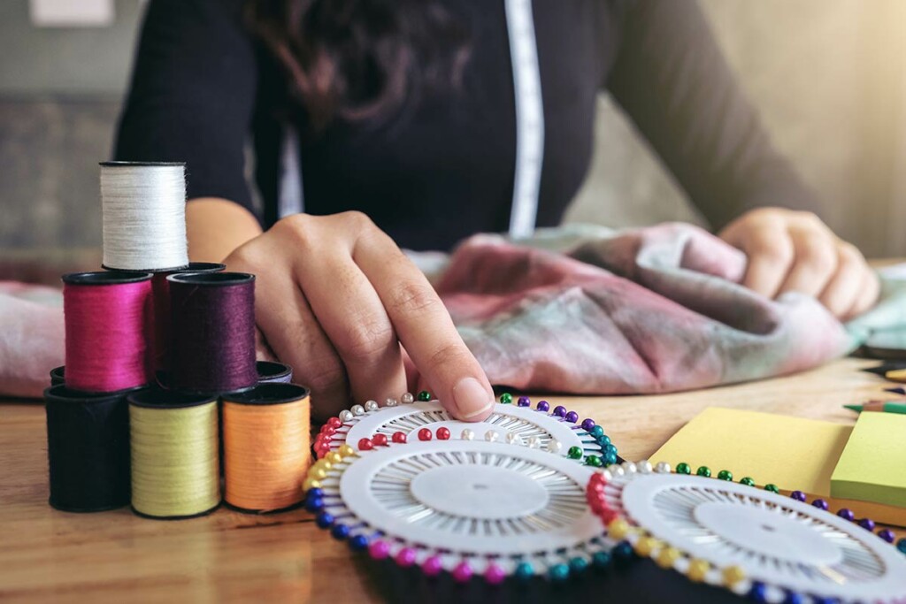 craft table with thread, buttons, and person holding button