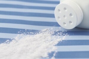 talcum powder spilling from white powder bottle onto blue and white striped surface