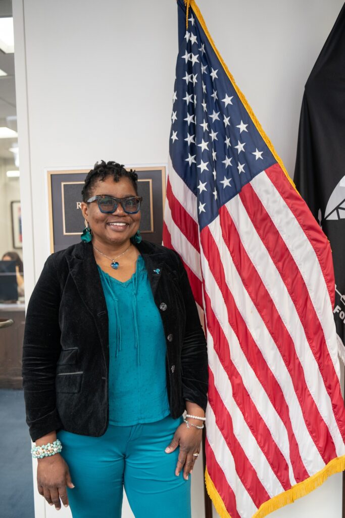 Vernelia, an OCRA Advocate Leader and ovarian cancer survivor, stands next to the American flag at OCRA's 2025 Advocacy Day.