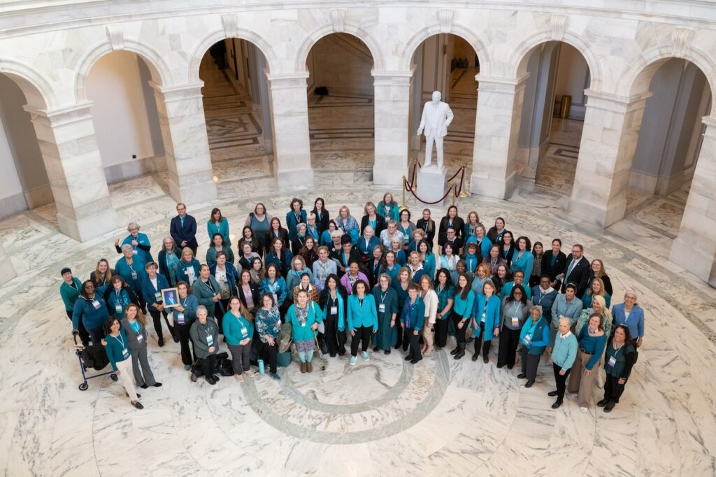 The full group of OCRA Advocate Leaders stand together in a sea of teal.