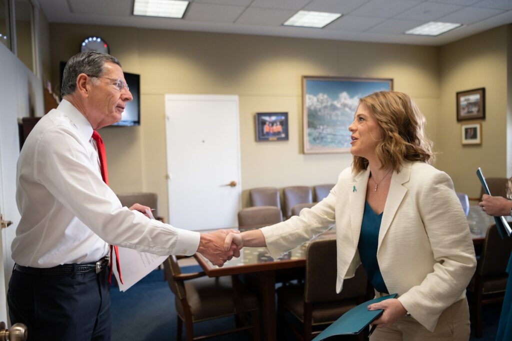 Photo of Tiffany, an OCRA Advocate Leader, shaking hands confidently with her Congressional representative in a legislative office setting.