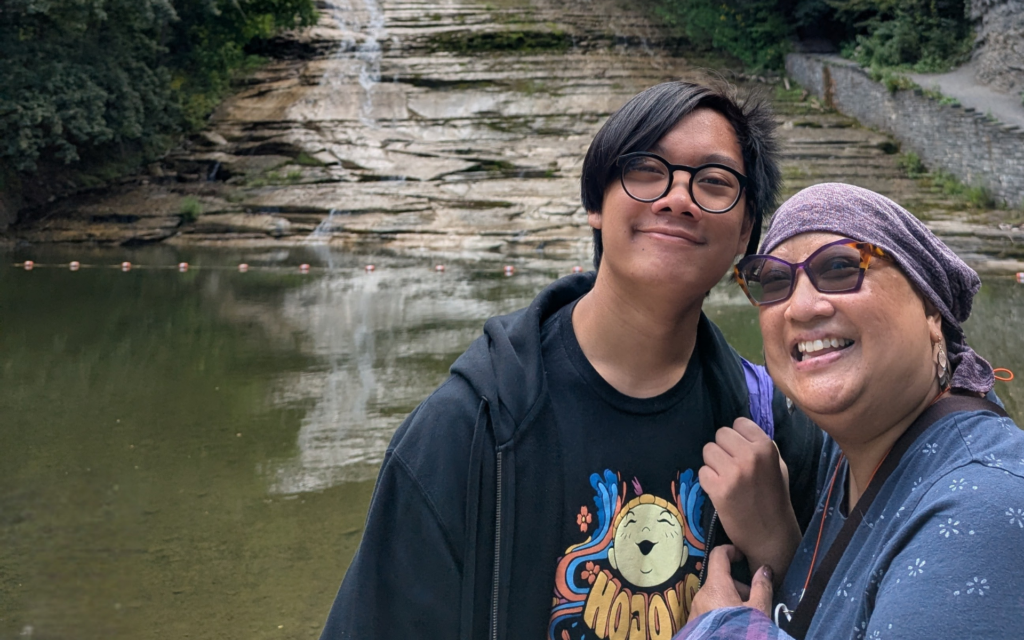A uterine cancer survivor and her son stand in front of a flowing river.