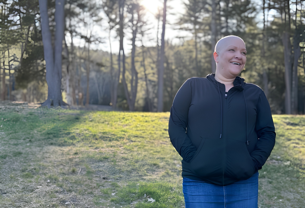 A bald woman, ovarian cancer survivor, takes a walk through a park on a sunny day